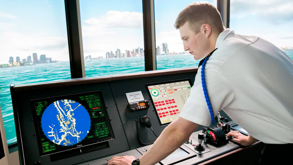 Male student with the TAMU Maritime Academy looking over controls of a ship.